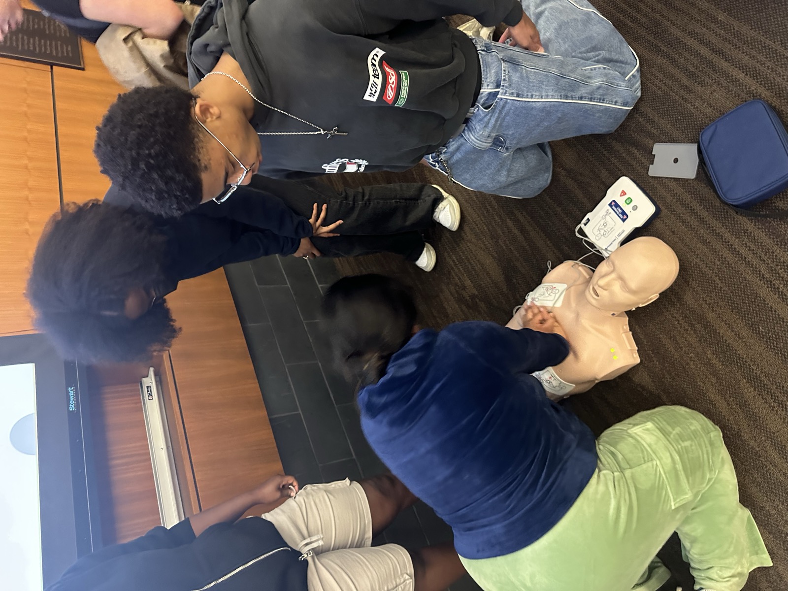 Students practicing hands only CPR with an AED